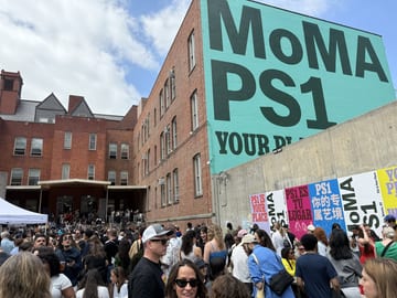 Crowd gathered outside the MoMA PS1 building beneath its large sign